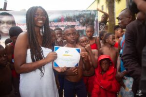 No Limit International Co-Founder Orlyola Tantchou holding up a certificate with a swimming camp participant.