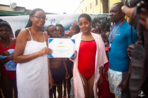 A No Limit International Co-Founder holding up a certificate with a swimming camp participant.