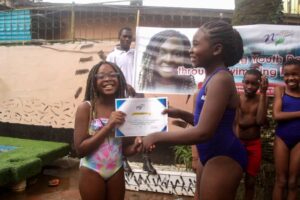 No Limit International Co-Founder Orlybella Tantchou holding up a certificate with a swimming camp participant.