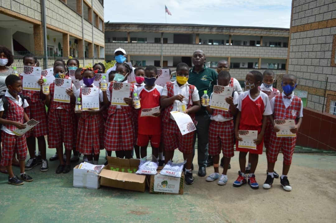 Students of Du Vaal International School holding up educational brochures on COVID-19, provided by No Limit International and FICOVID-19. In front of the students are boxes of additional brochures and healthcare supplies.