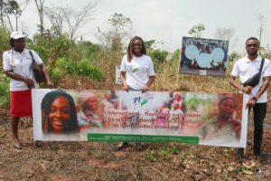 No Limit International Co-Founder Orlyanka Tanchou and two others hold a No Limit International banner that reads: “No Limit International - Promoting sustainable livelihoods by providing land to farm opportunities to communities in need.”